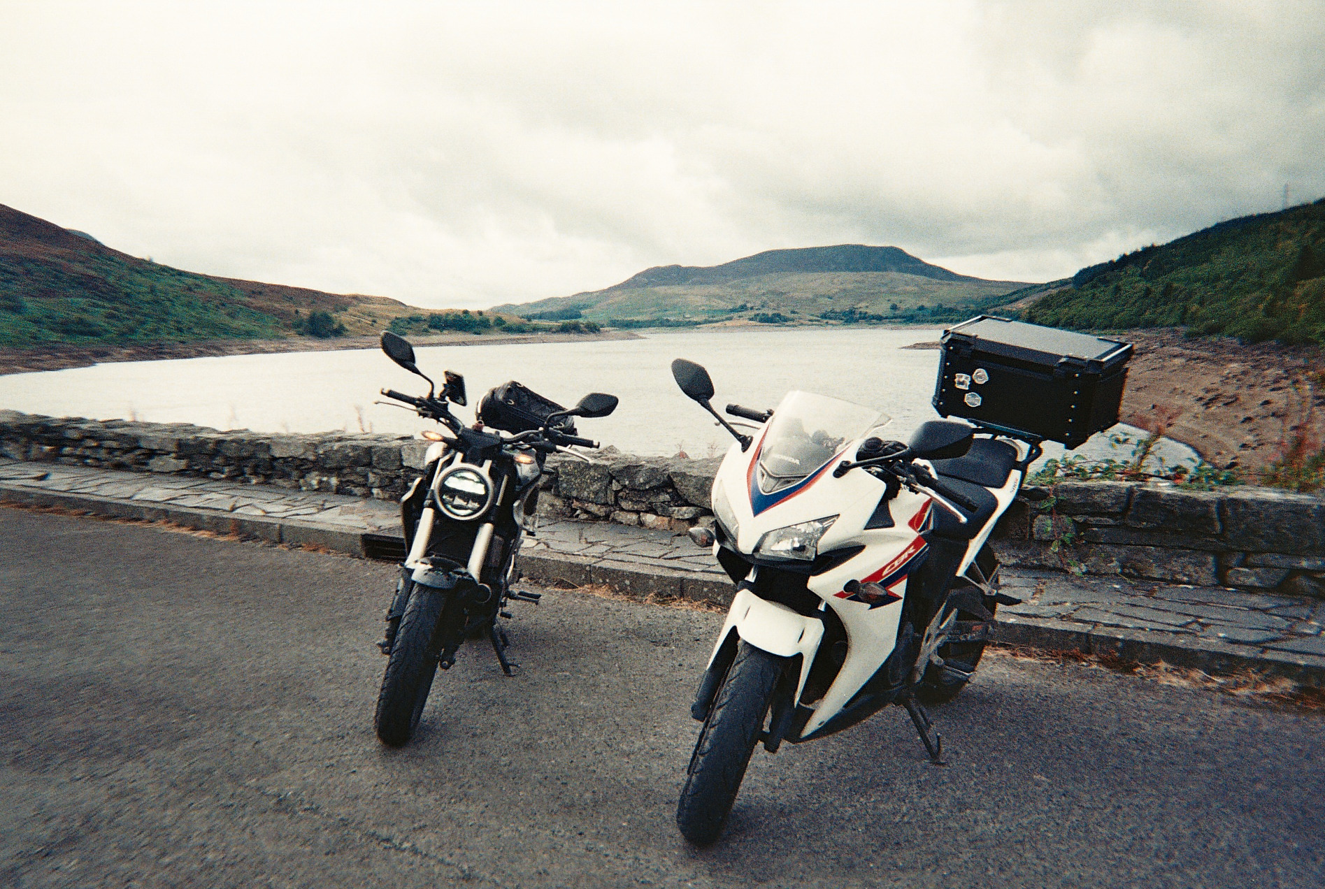 Two motorcycles parked beside a lake